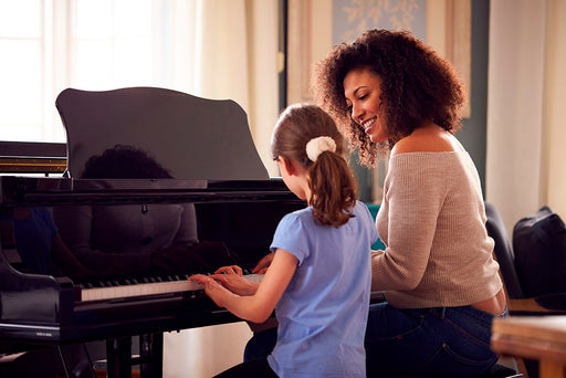 a woman sitting with a young girl at the piano