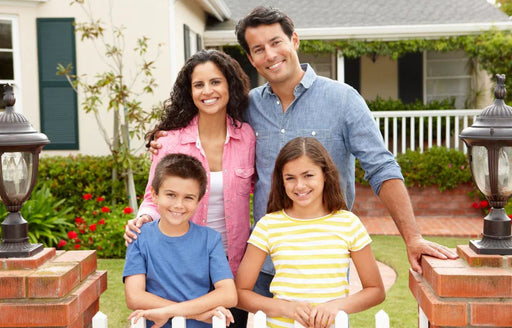 A happy family of four standing outside their home that is free from a moth infestation