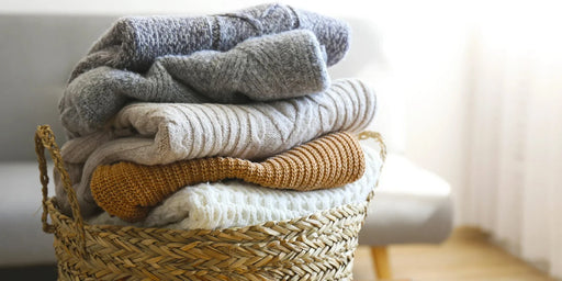 A wicker-basket full of thick sweaters that are free from a clothes moth infestation.