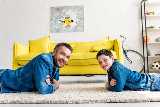 a happy father and son lying on their lounge carpet at home