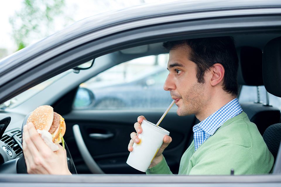 man drinking and eating in his car