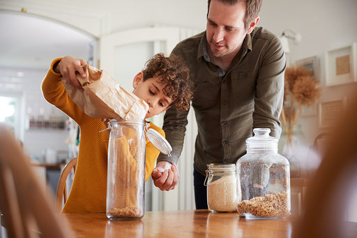 a father helping his son to put dry food stuffs into sealed containers