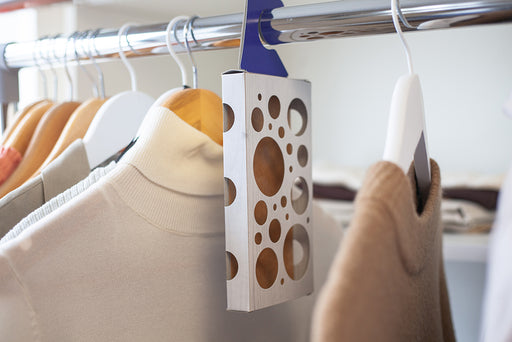 a Moth-Prevention Moth Trap hanging in a closet full of clothes