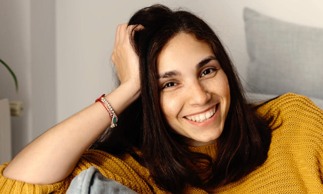 smiling woman wearing a wool sweater sat on a sofa