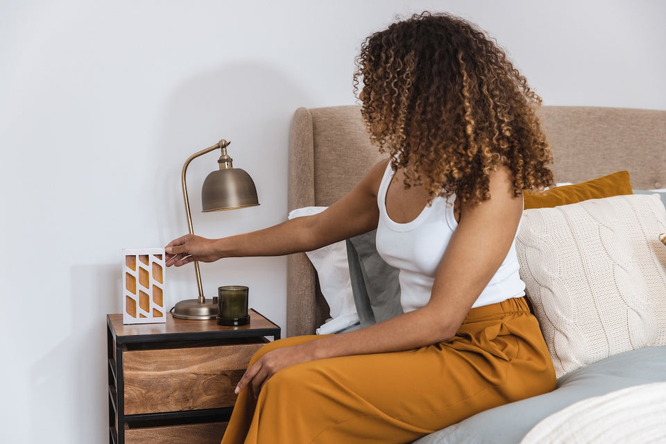 a woman placing a moth trap on her bedside table
