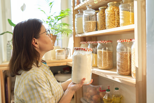 a woman placing a storage jar of flour onto a shelf of sealed containers