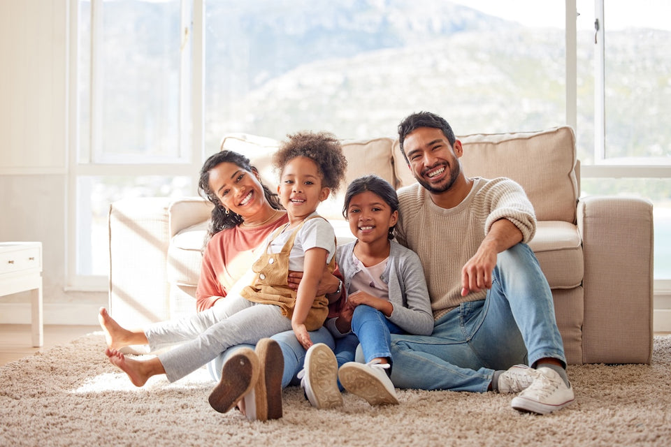 a family group sitting on their carpet looking relaxed and happy