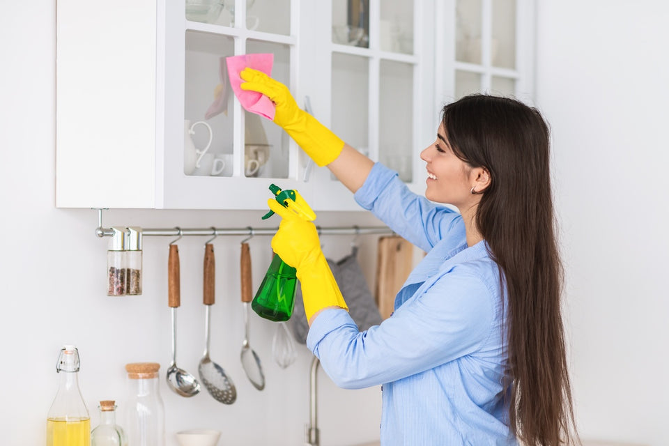 a woman cleaning her kitchen cupboards to help prevent pantry moths