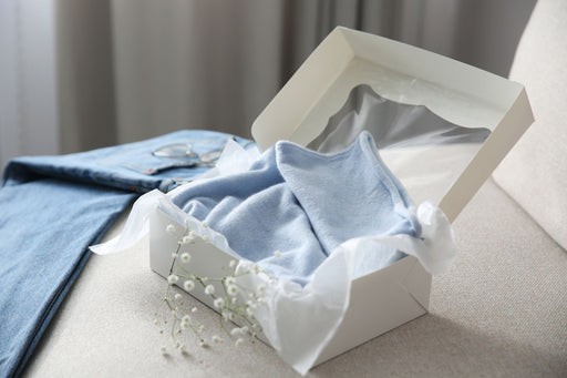 a gift box with a baby blue cashmere sweater inside, with matching denims