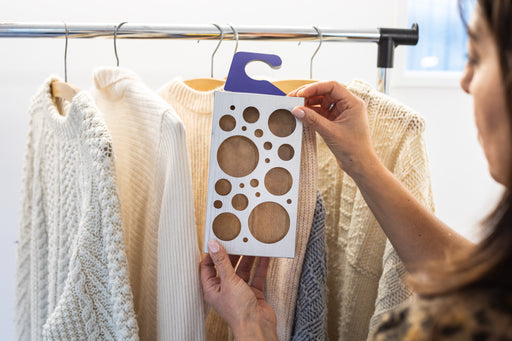 a Moth Trap being hung on a clothes rail with woolen sweaters