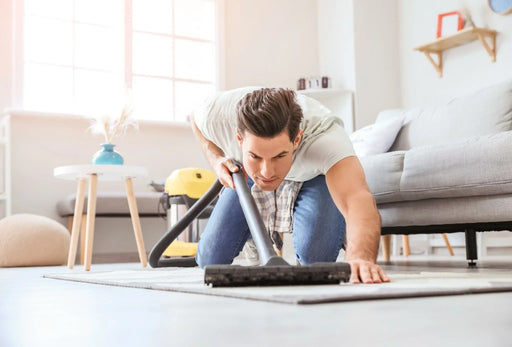 A man on his hands and knees hooving up a carpet moth infestation