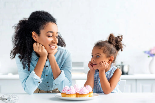 A mother and daughter baking cakes in their kitchen that is free from a pantry moth infestation. 