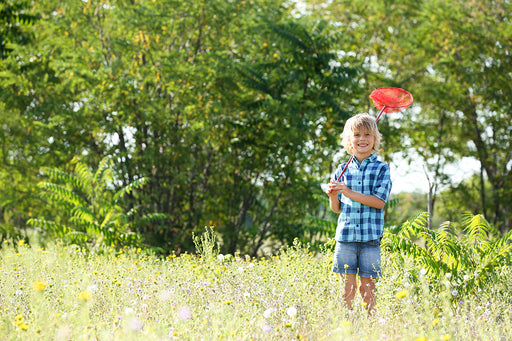 a boy holding a net to catch moths in the garden