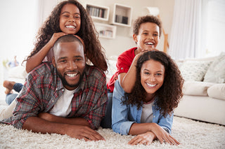a happy family of four lying on their carpet in the living room