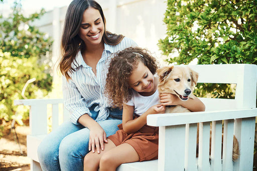 a mother and daughter sat outside on a bench with their family dog, who eats food that is free from a pantry moth infestation