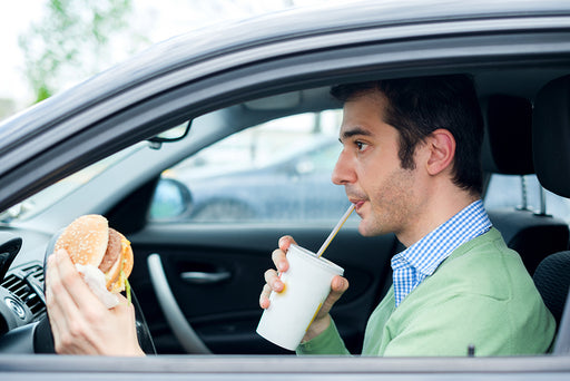  man drinking and eating in his car