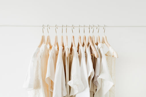 a selection of cream-colored beautiful clothing on a hanging rail