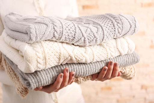 hands holding a neat clean pile of woolens