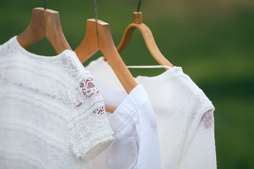 some fresh white clothing airing outdoors on wooden hangers