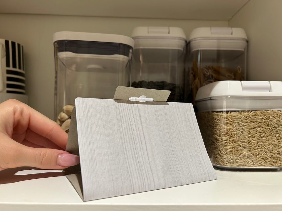a close up of a MothPrevention Pantry Moth Trap in a cupboard with dry foods stored in containers