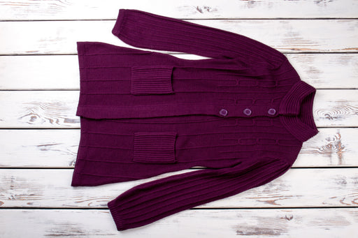 a dark purple colored cardigan lying flat