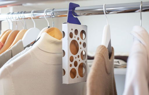 a MothPrevention Moth Trap hanging in between woolen garments