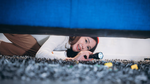 a girl checking under her bed using a torch