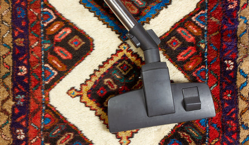 a patterned woolen rug being vacuumed
