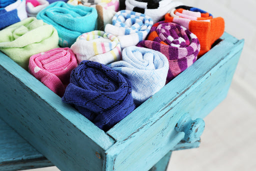 an open drawer full of rolled up colorful socks