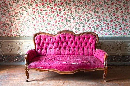 a fuschia antique button back couch with damage to the seat