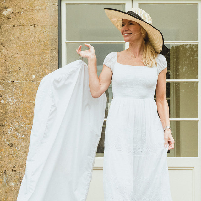 woman wearing a white dress holding a garment bag