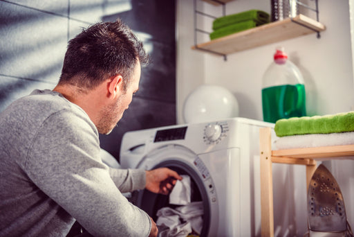 man putting clothing into the washing machine
