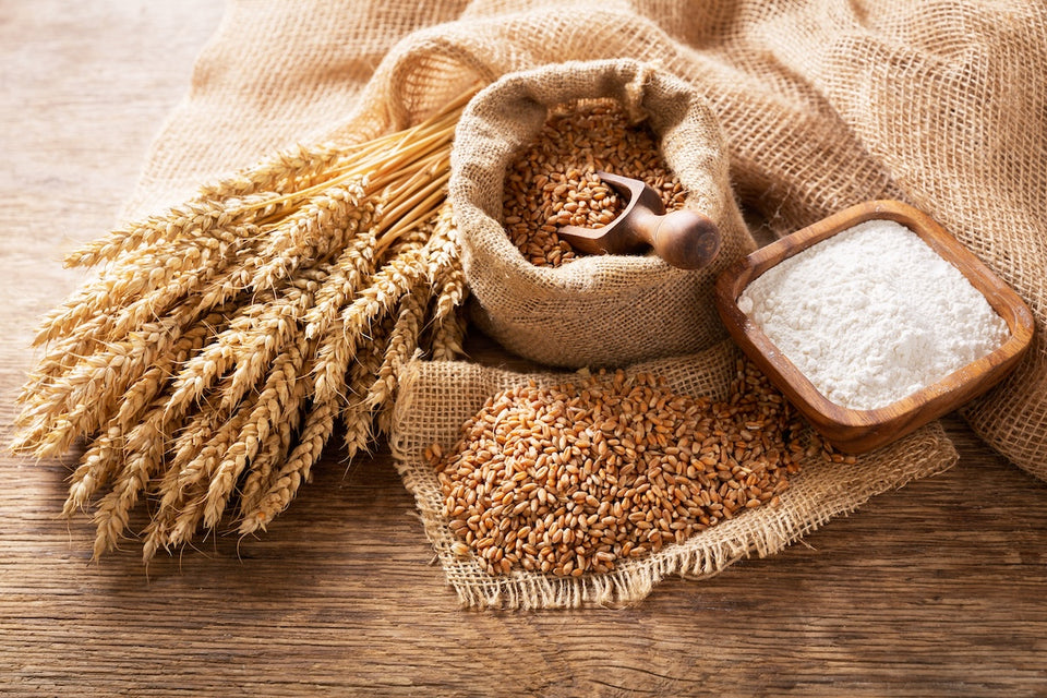 sheaves of wheat, wheat grain and flour on a table