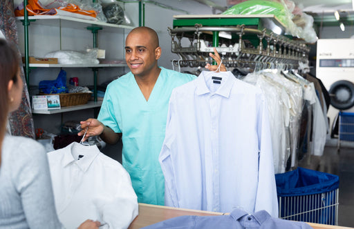 a dry cleaning person handing over some cleaned shirts to a customer