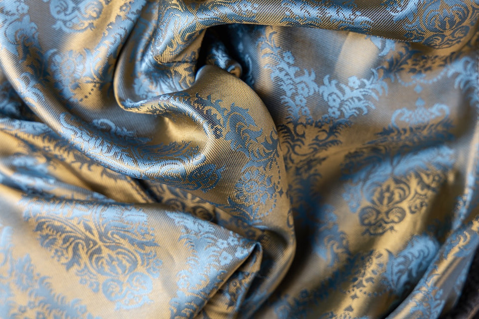 a close up of a blue and gold patterned vintage silk scarf