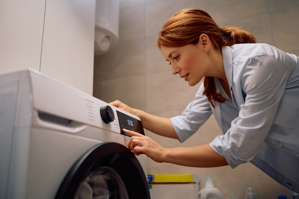 a woman setting the temperature on her washing machine